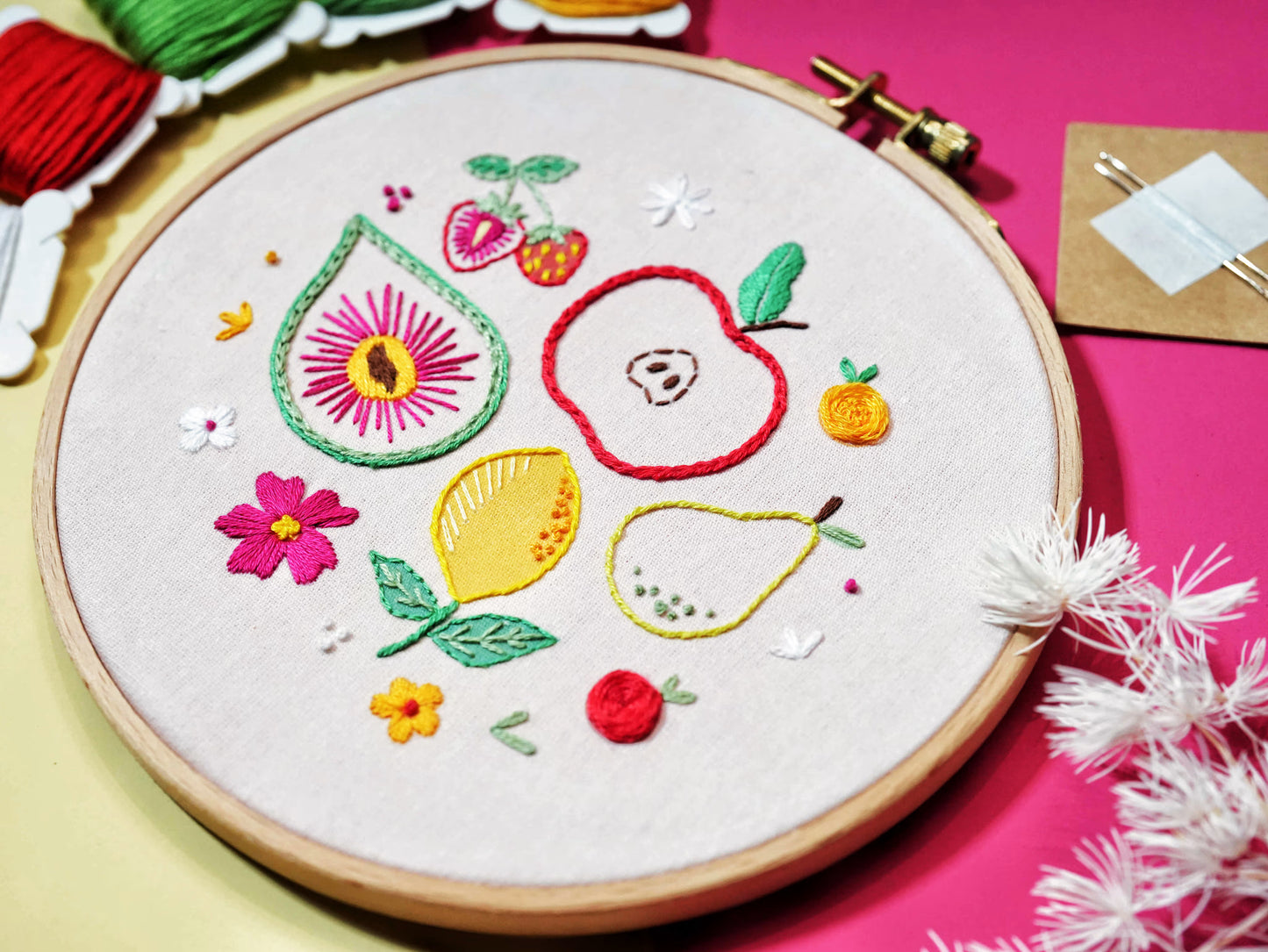 Close-up of Fruity Fiesta Embroidery Kit hoop featuring apple, pear, lemon, strawberry, and floral embroidery details with vibrant colors.