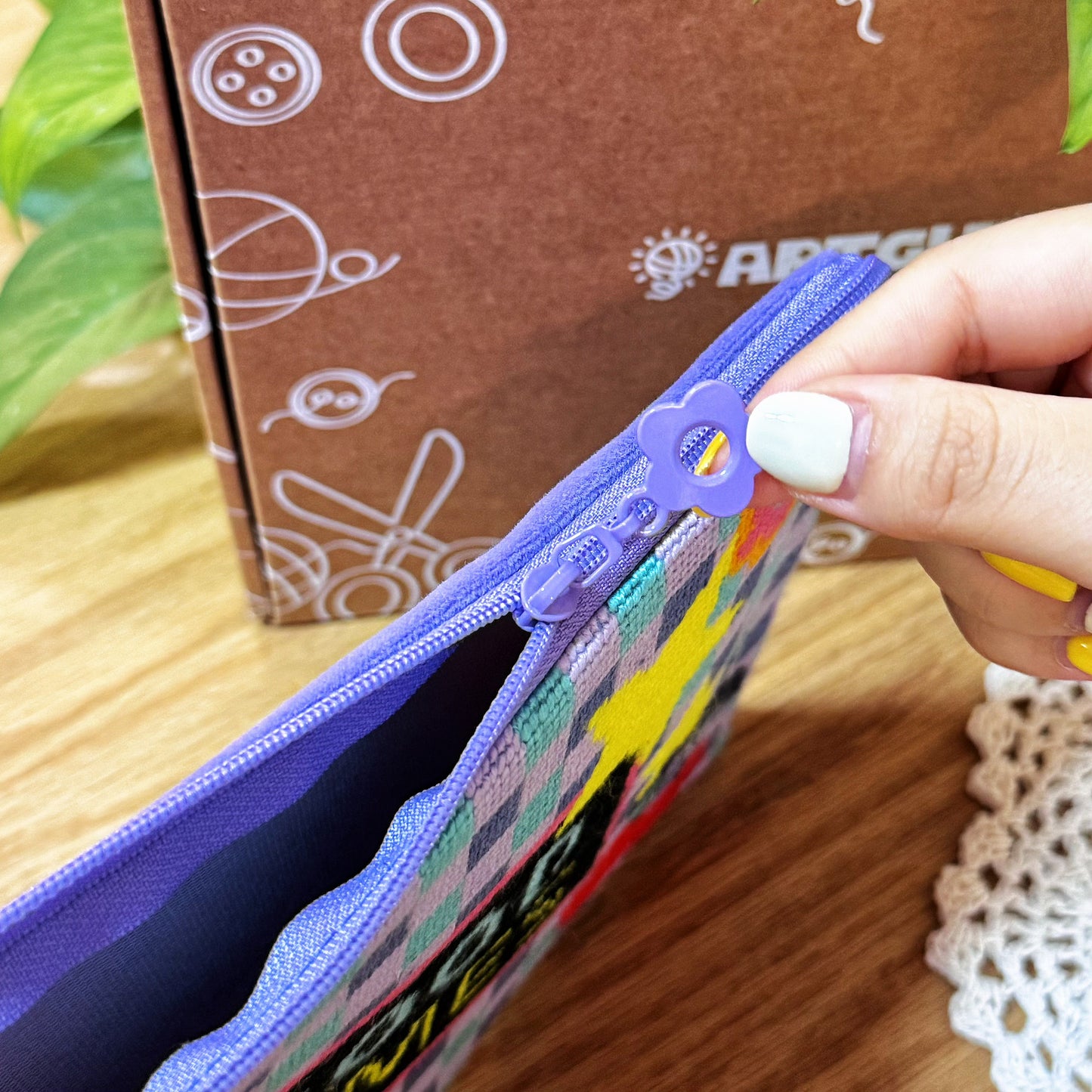 Close-up of the purple zipper pull being opened on the Good Times Half-Stitch Kit pouch, highlighting stitch detail.