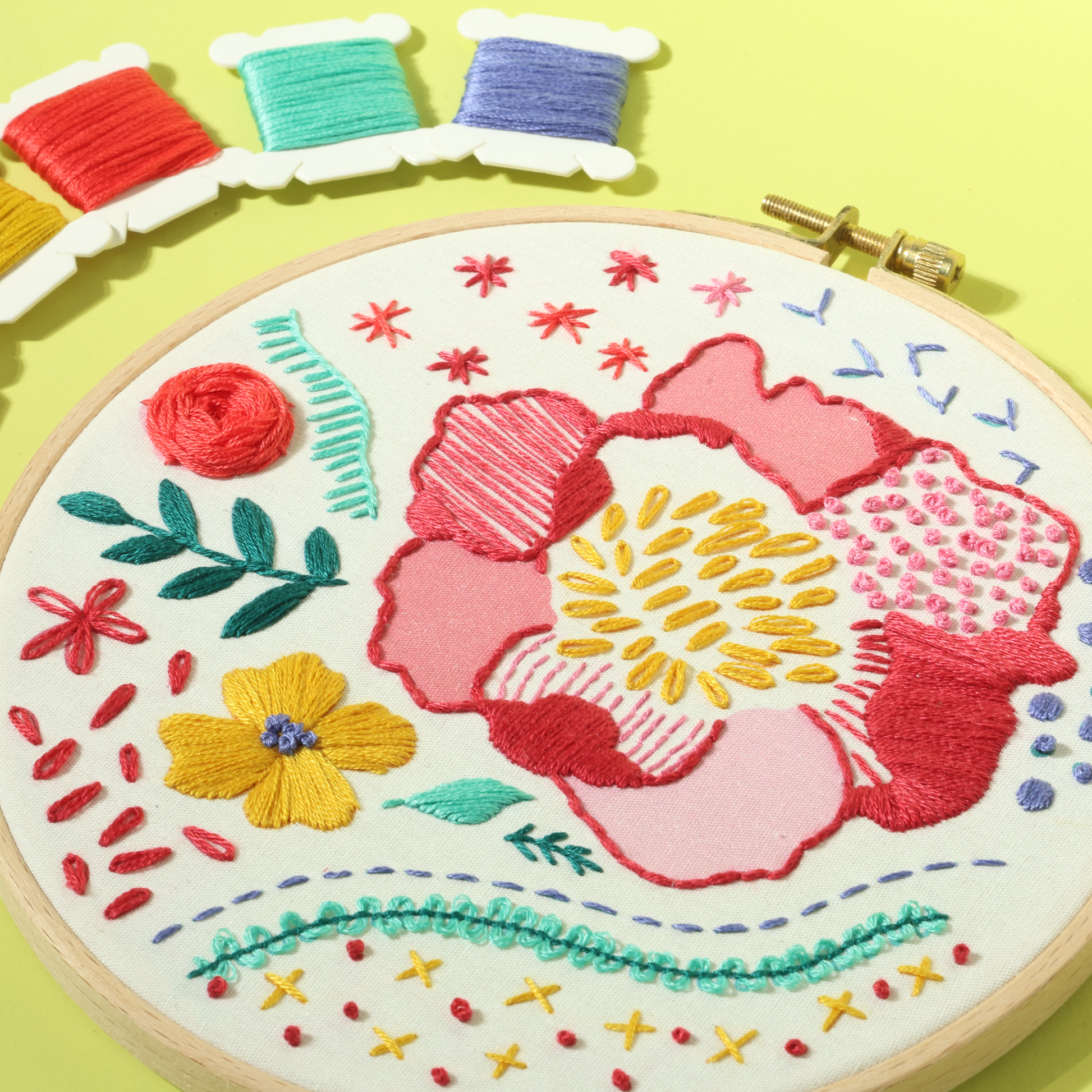 Close-up of floral embroidery hoop showing colorful stitches and thread details.