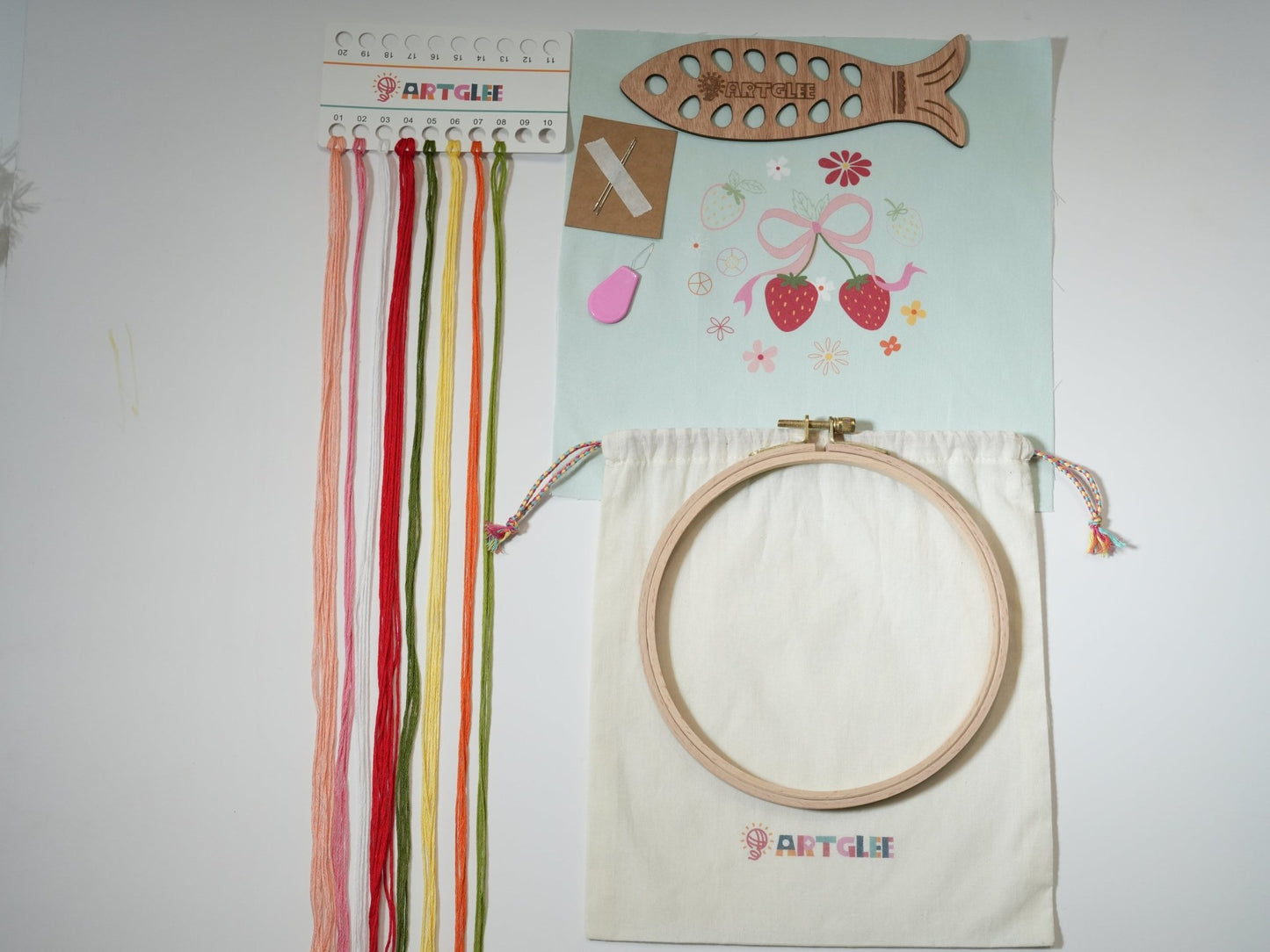 Full Sweet Strawberry embroidery kit contents with printed fabric, colorful threads, fish-shaped thread board, hoop, and cotton bag.