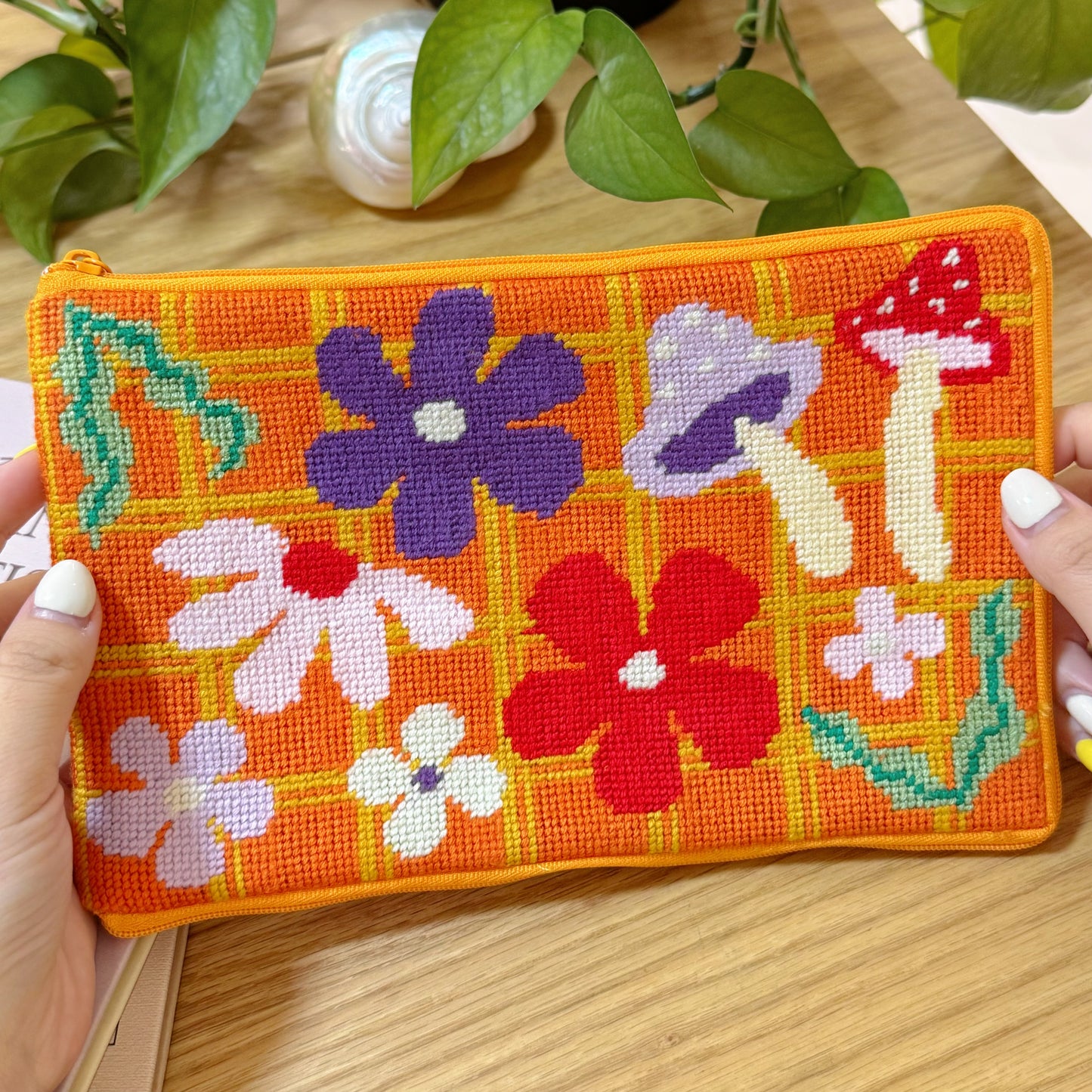 Bloom Daisy Half-Stitch Pouch held in hand, showing detailed stitches and vibrant flowers