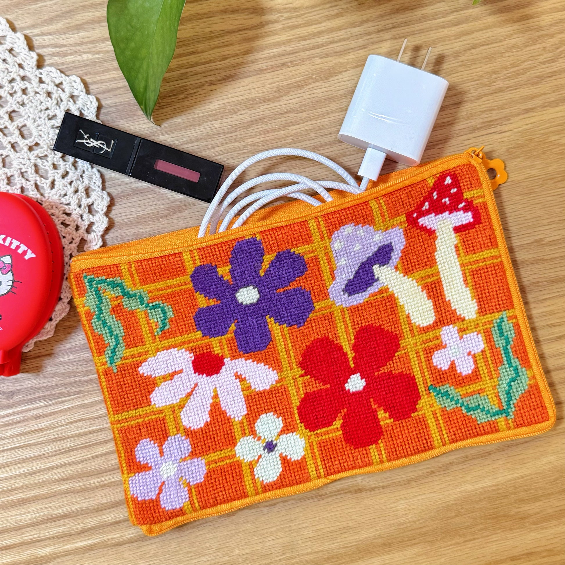 Bloom Daisy Half-Stitch Pouch used for storing charger cable and lipstick accessories