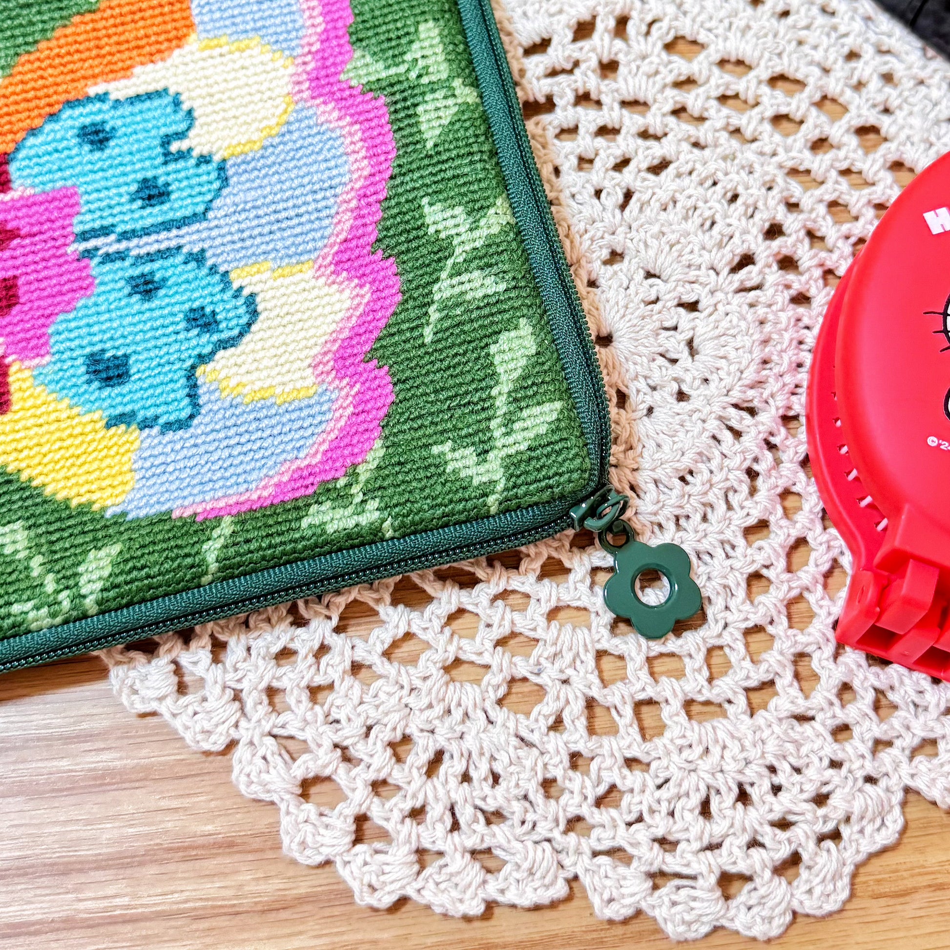 Close-up of the green zipper with flower-shaped puller on the Butterfly Garden Half-Stitch Kit pouch.