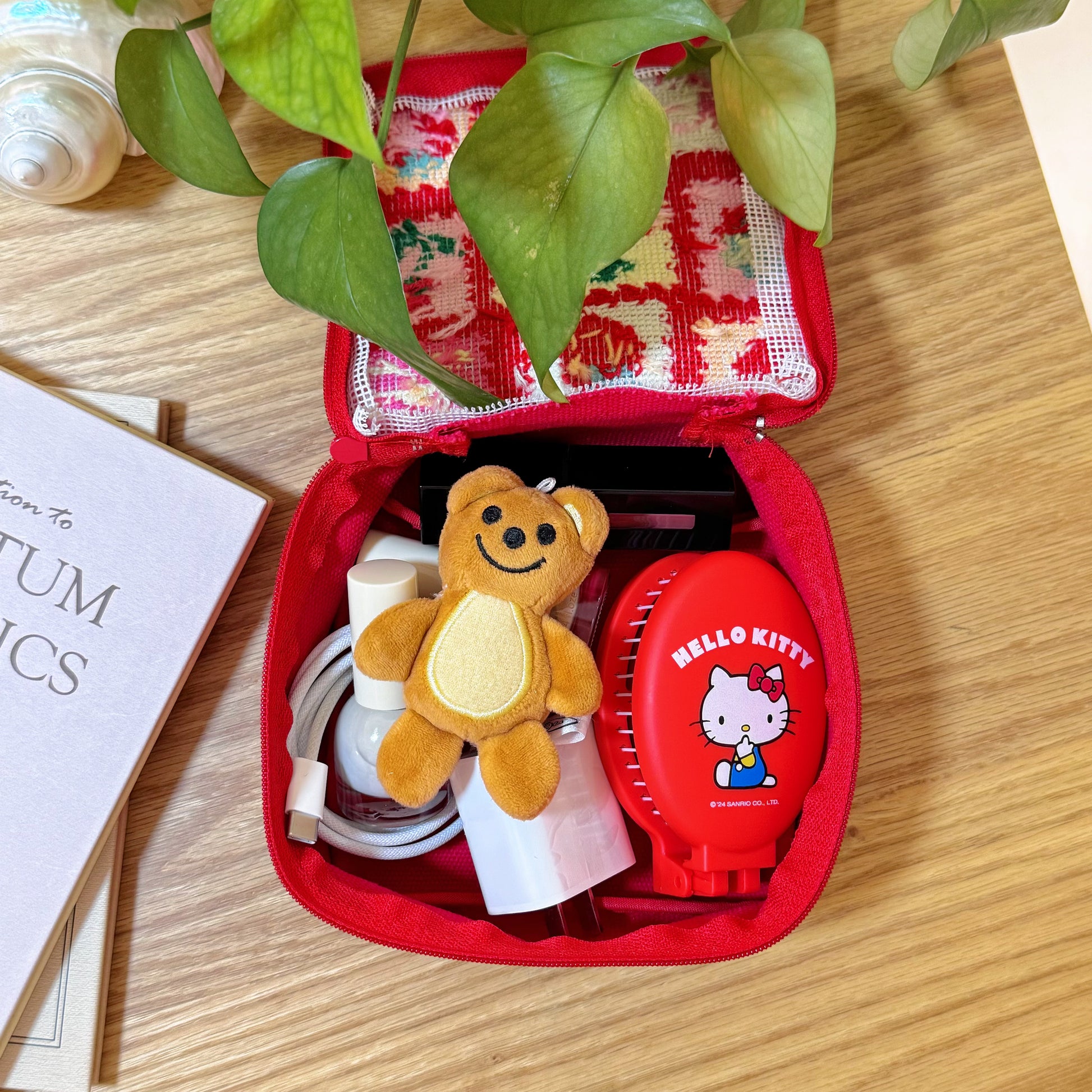 Inside of Cherry Love Half-Stitch pouch, storing Hello Kitty brush, teddy bear keychain, and charger cable.