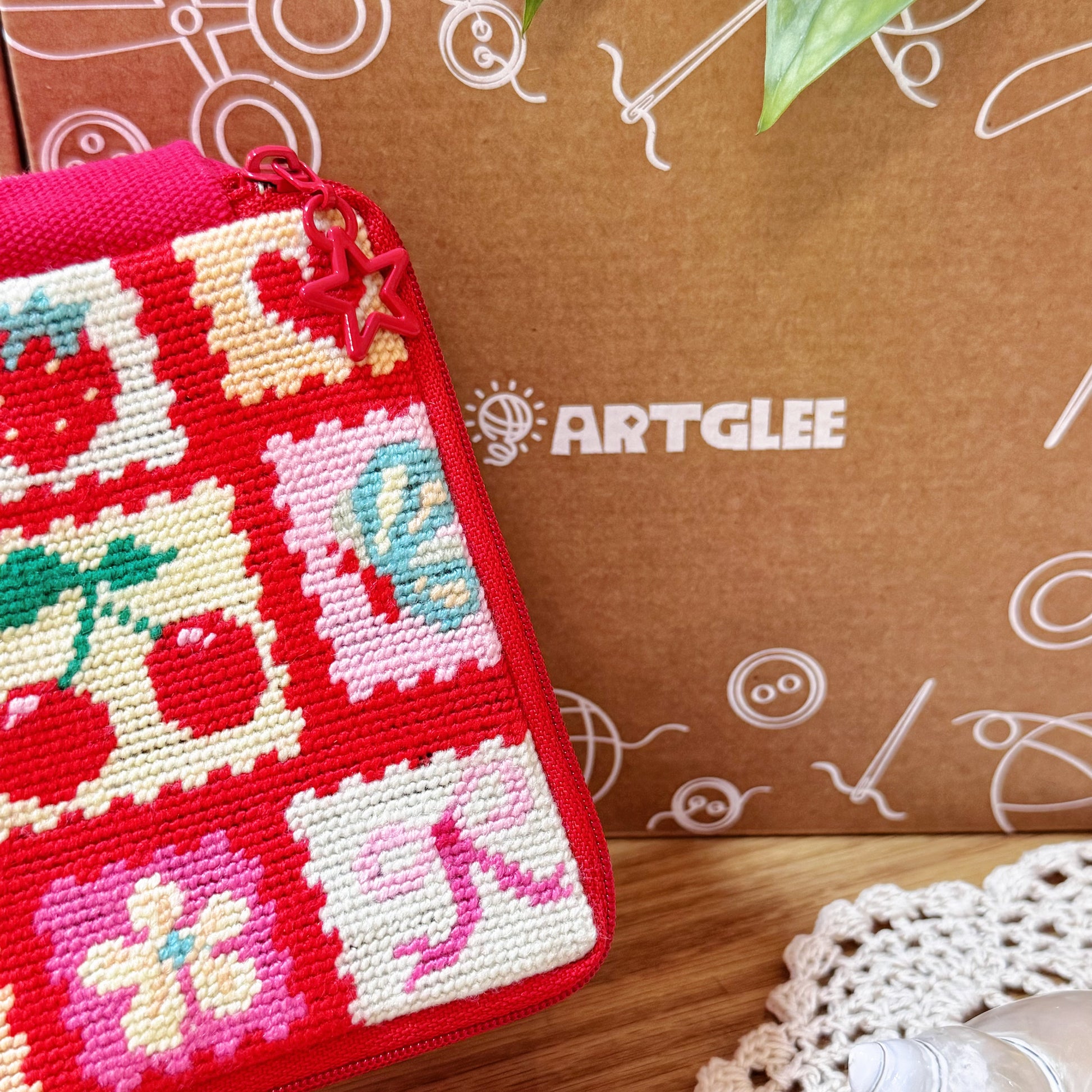Cherry Love Half-Stitch Kit pouch placed in front of Artglee branded kraft box packaging.