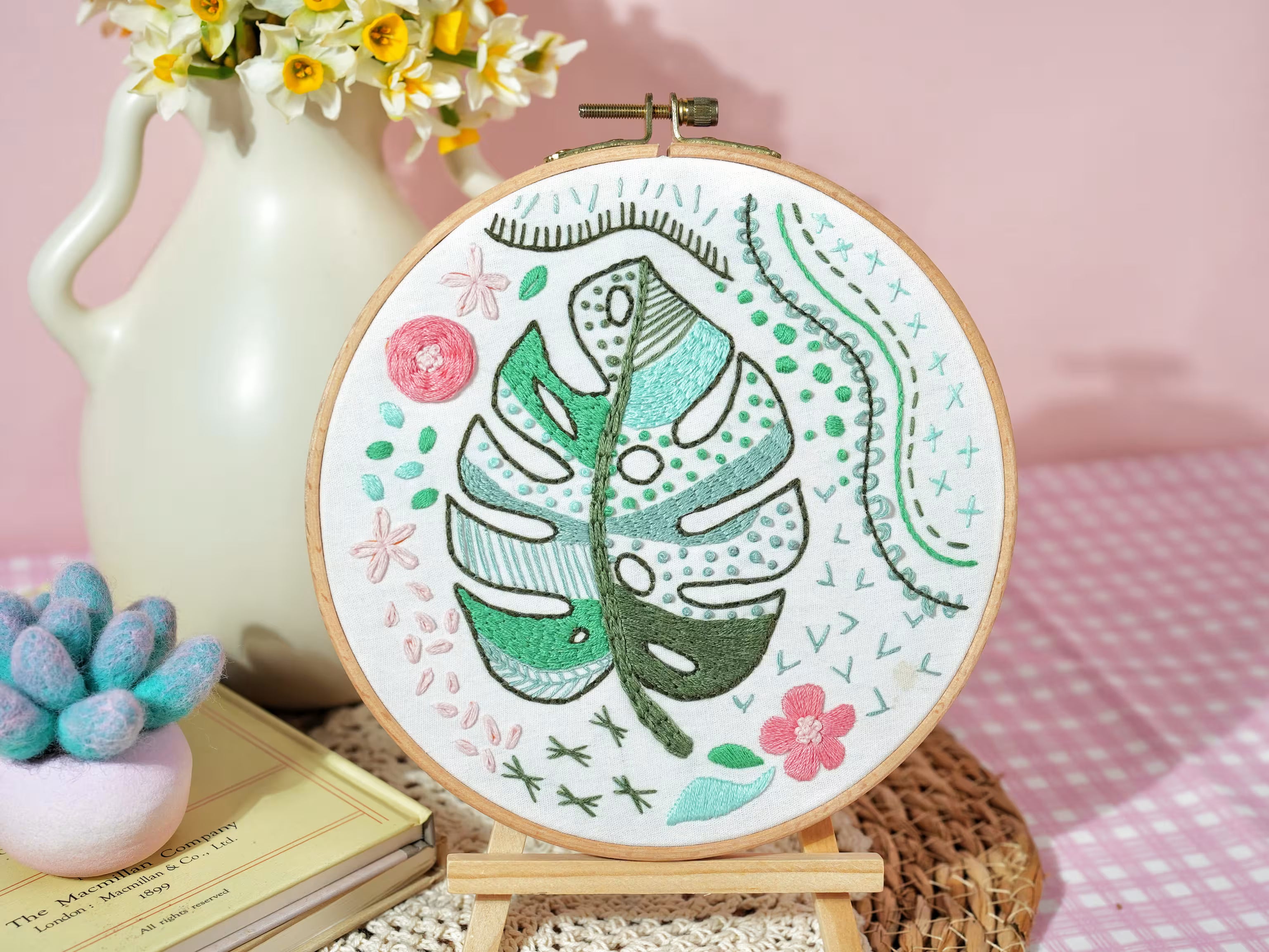 An embroidery hoop with a stitched green leaf motif and decorative embroidery patterns, representing the embroidery kit category.