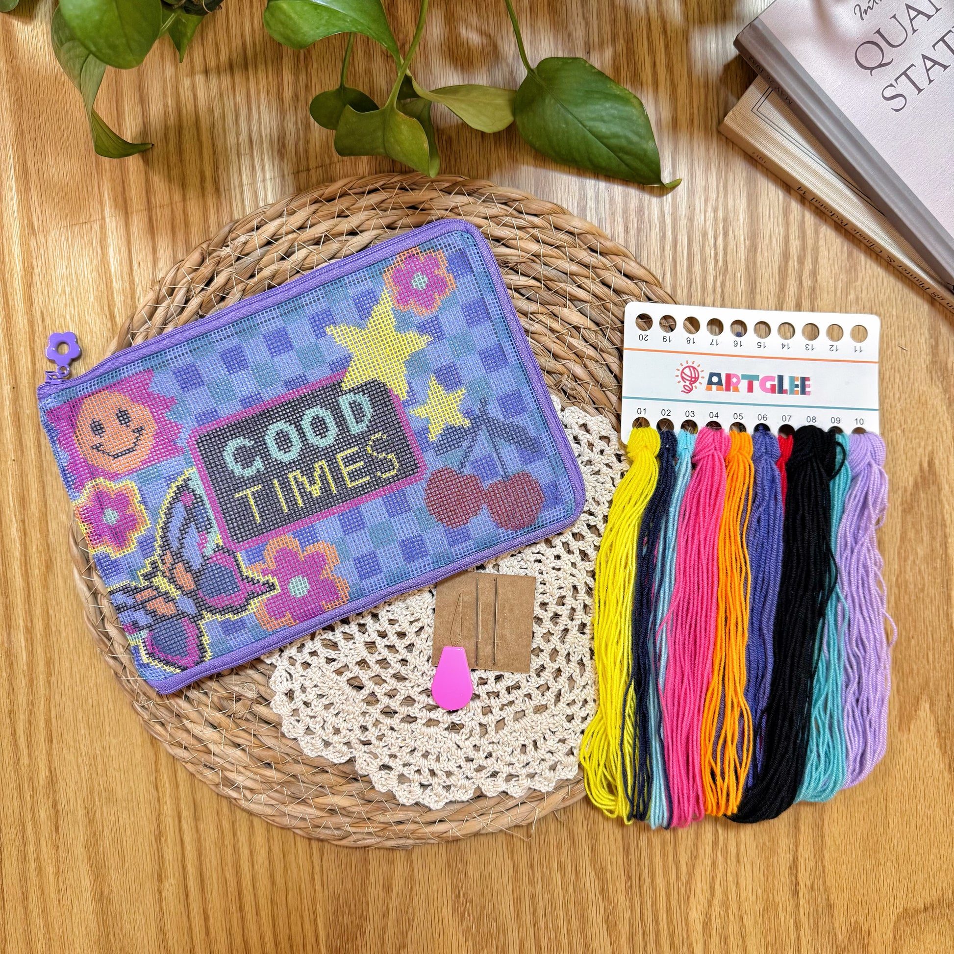 Good Times Half-Stitch Kit materials including pouch with stitched design, colorful embroidery threads, and accessories on a woven mat.