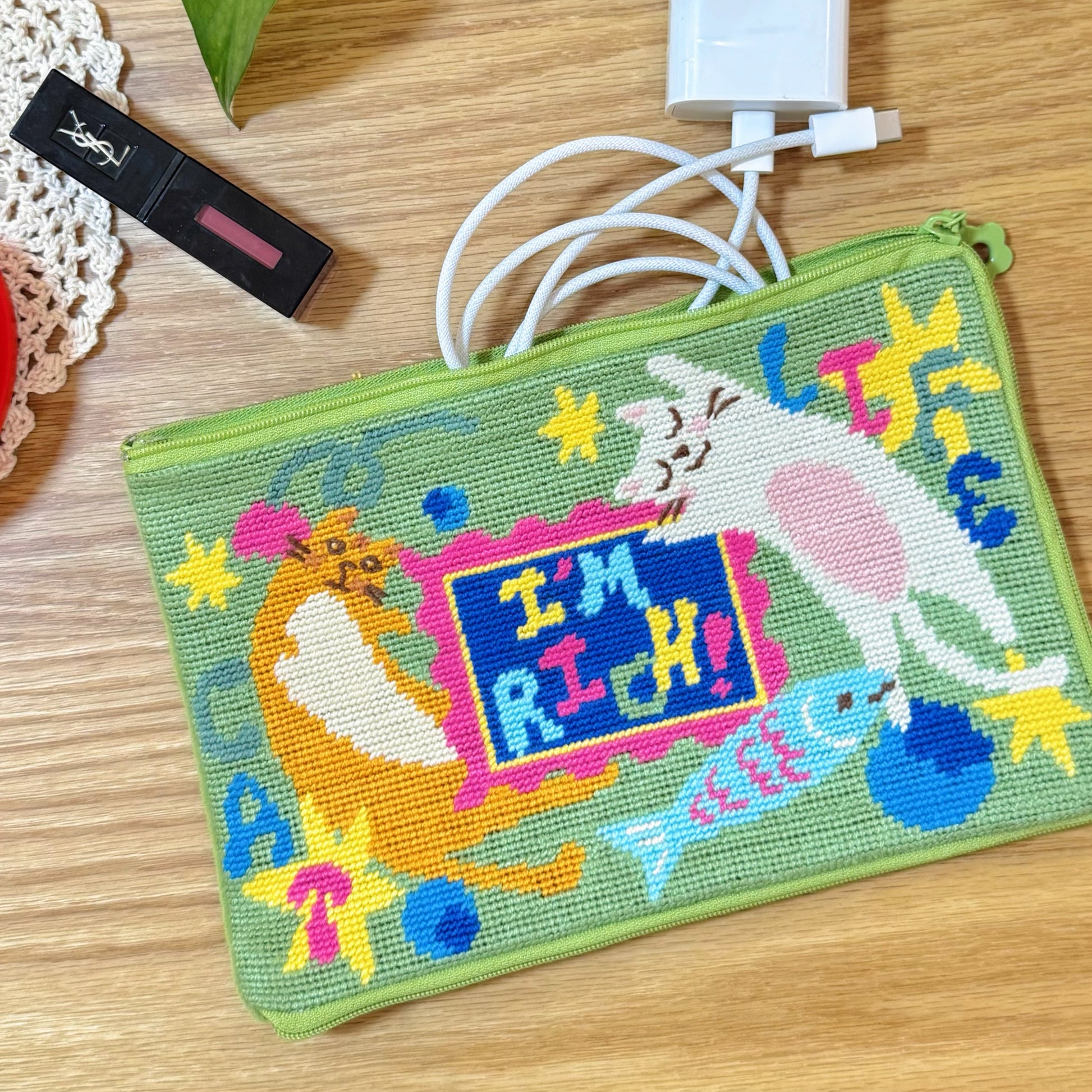 Lucky Cats half-stitch pouch used for storage, holding lipstick and charging cable.