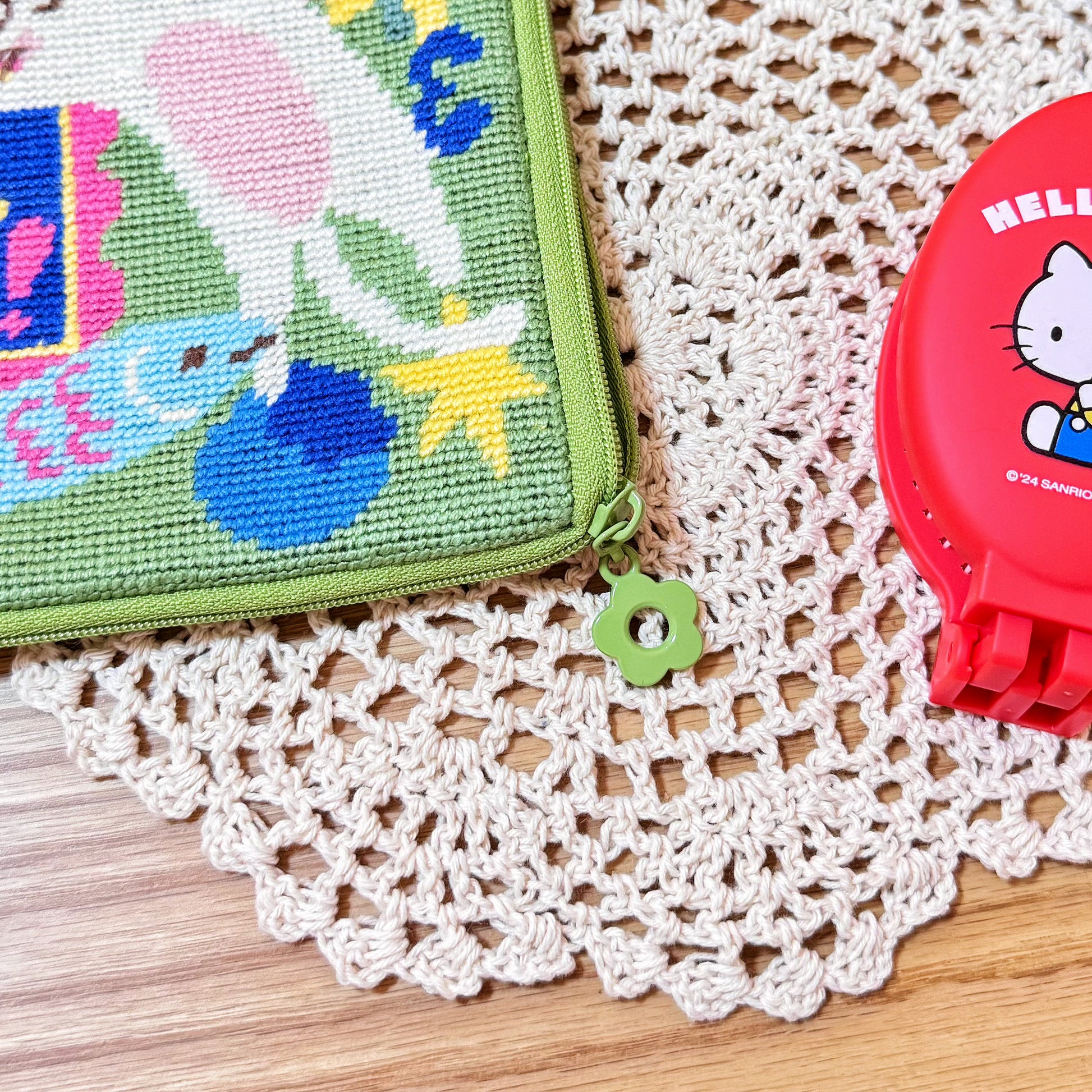 Close-up of the Lucky Cats half-stitch pouch zipper with green flower-shaped pull.