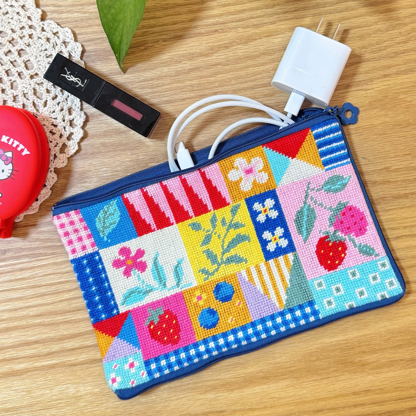 Finished Patchwork Garden Half-Stitch Kit pouch used for storage with lipstick and charger inside