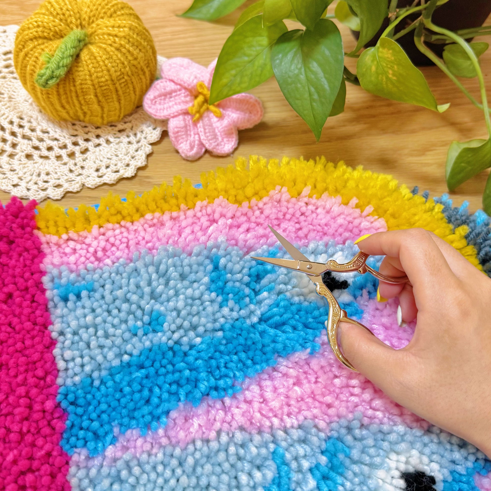 Hand using scissors to trim yarn on Sardine Delight latch hook rug kit