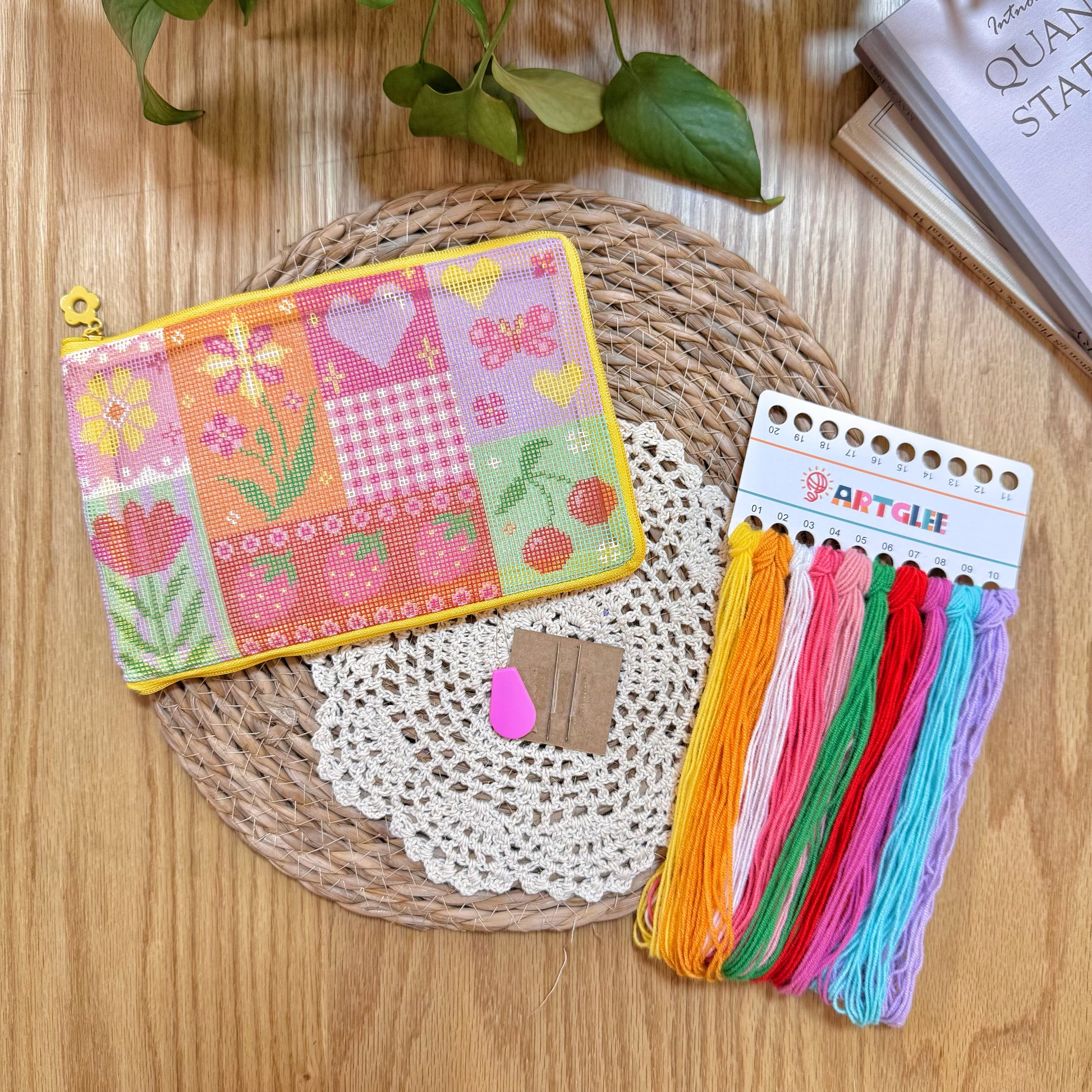 Embroidery kit materials including patchwork pouch, colorful yarns, needles, and accessories.