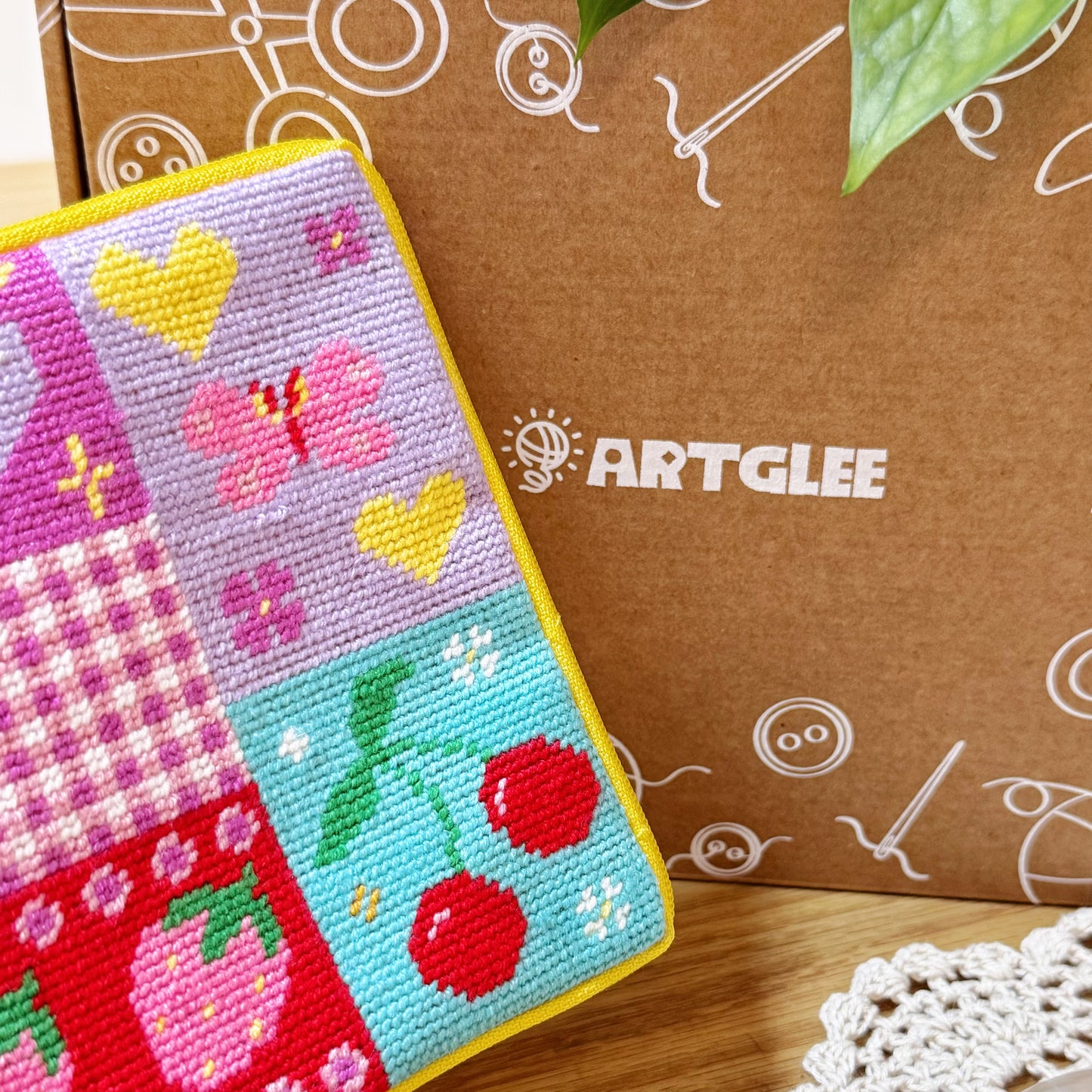 Patchwork pouch with cherry and butterfly design placed in front of Artglee branded box.