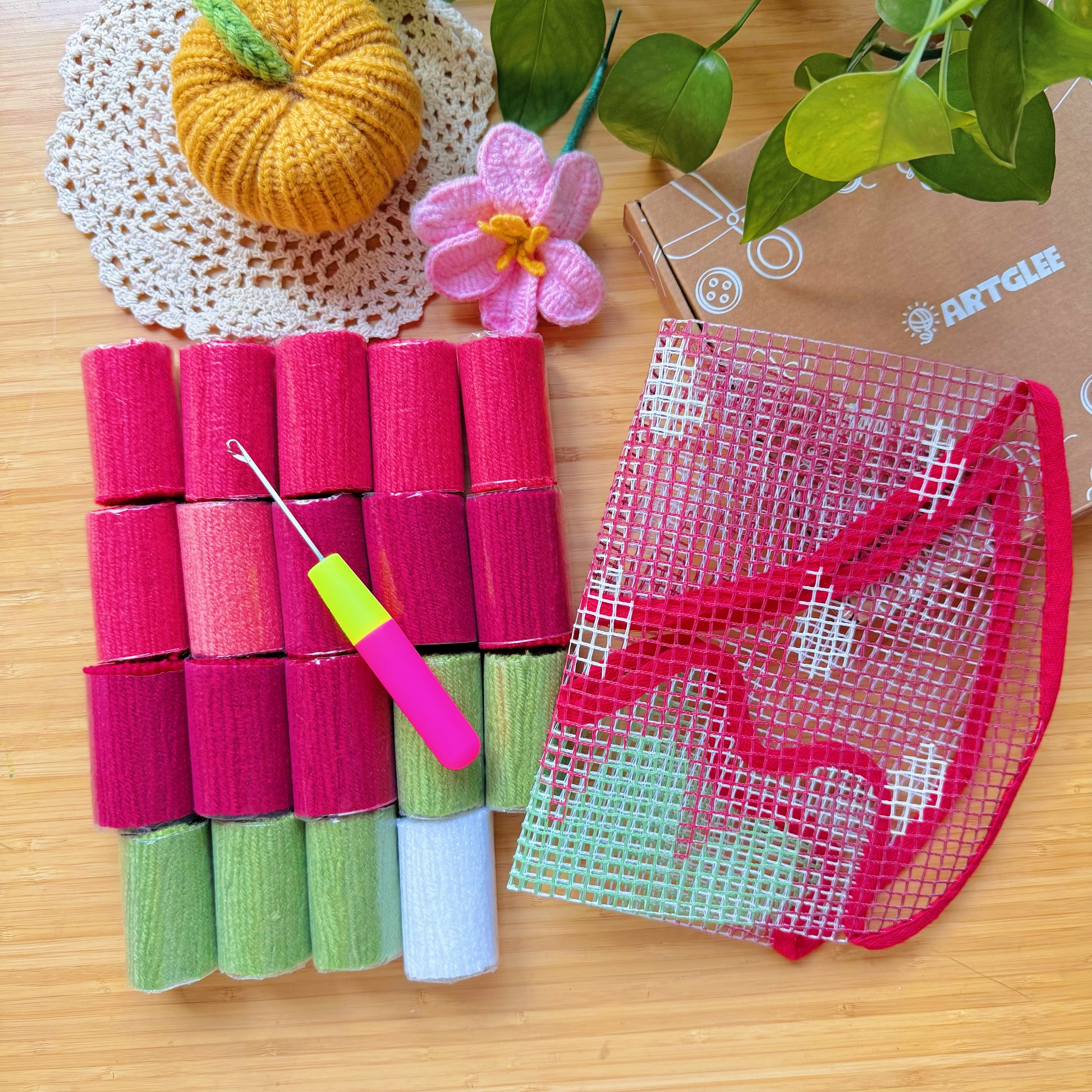 Unpacked yarn rolls, latch hook tool, and printed mesh canvas for Sweet Strawberry latch hook kit