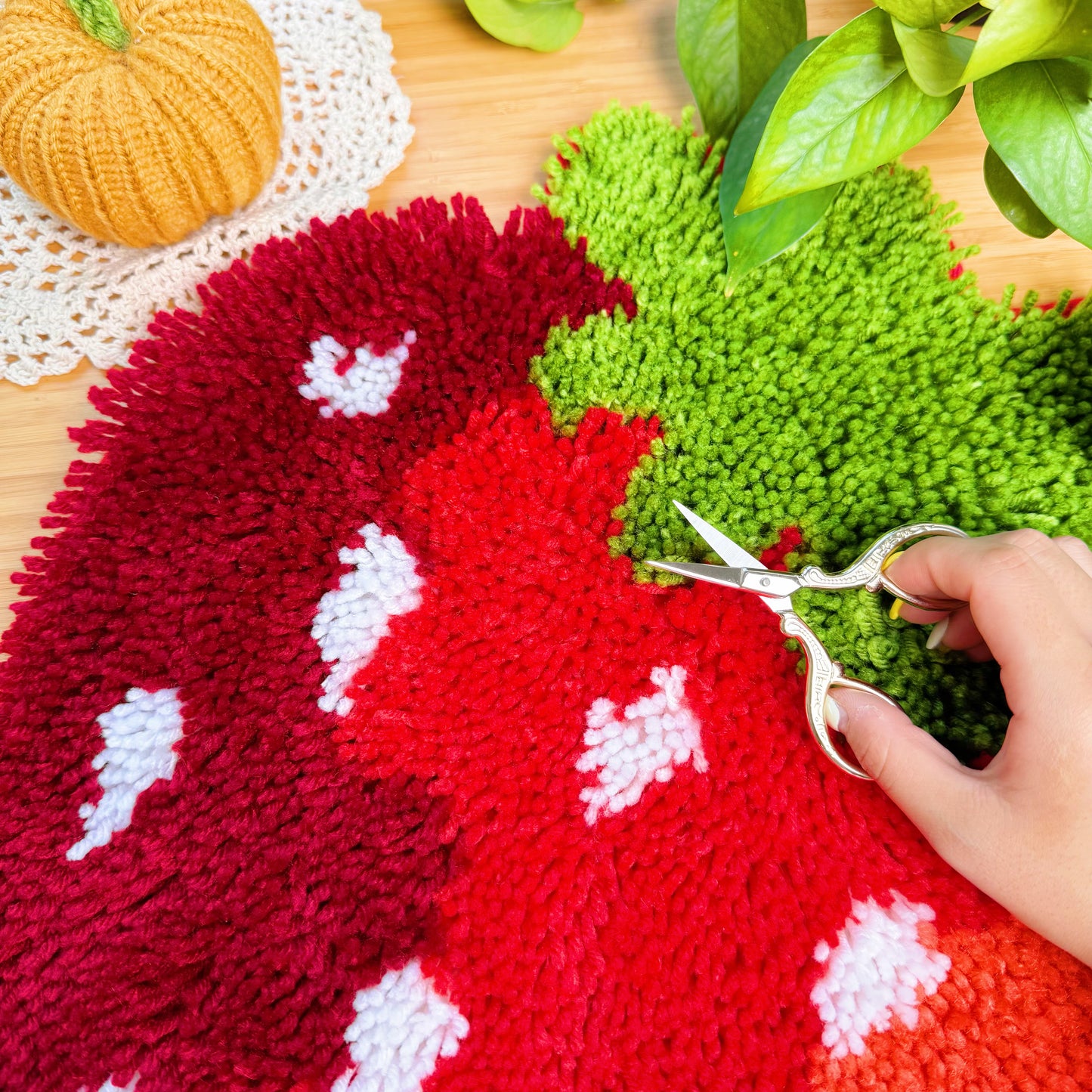 Hand trimming yarn edges of the Sweet Strawberry latch hook mat with embroidery scissors